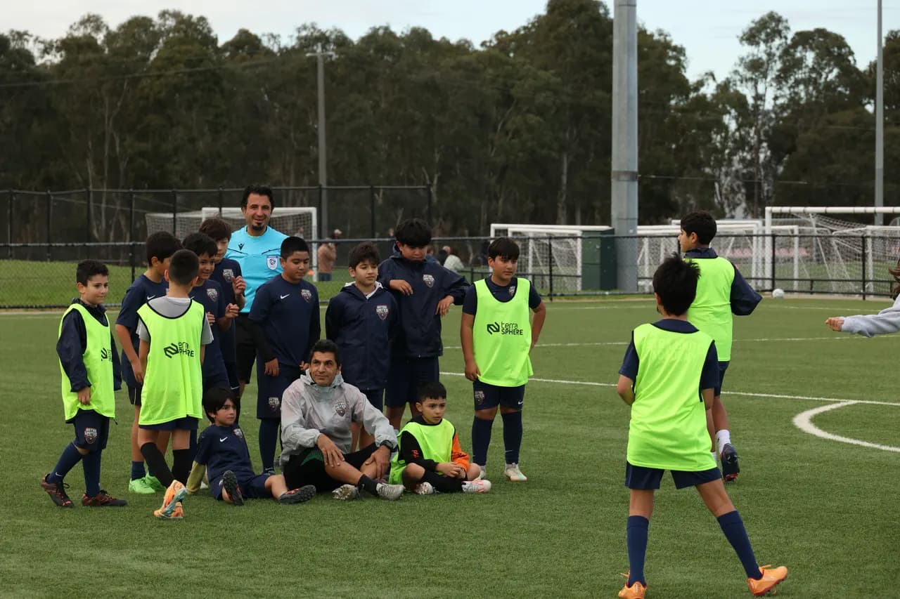 Astra United coaches and advanced youth players in a high-intensity training huddle on the Darebin pitch