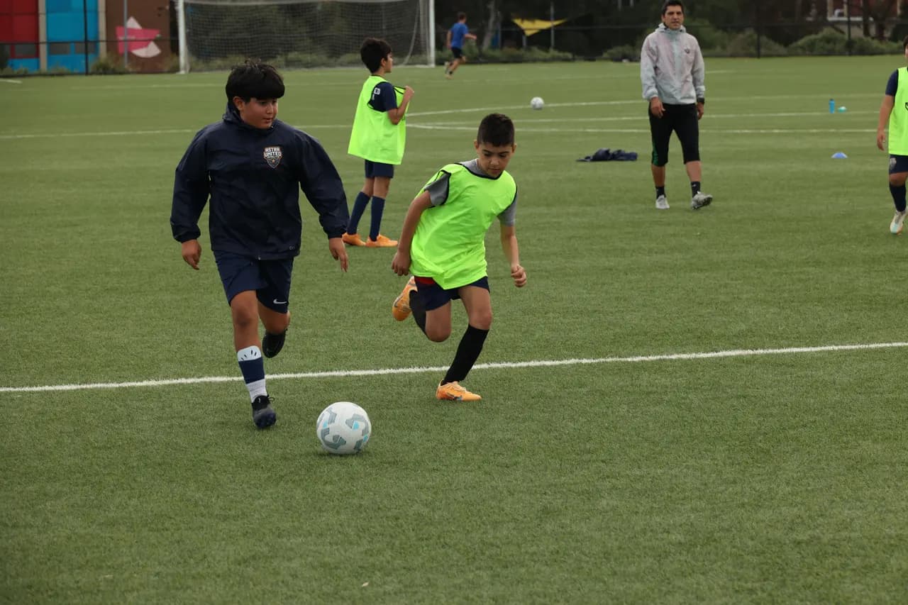 Astra United youth player in navy kit dribbling past a defender during an academy training session at Darebin