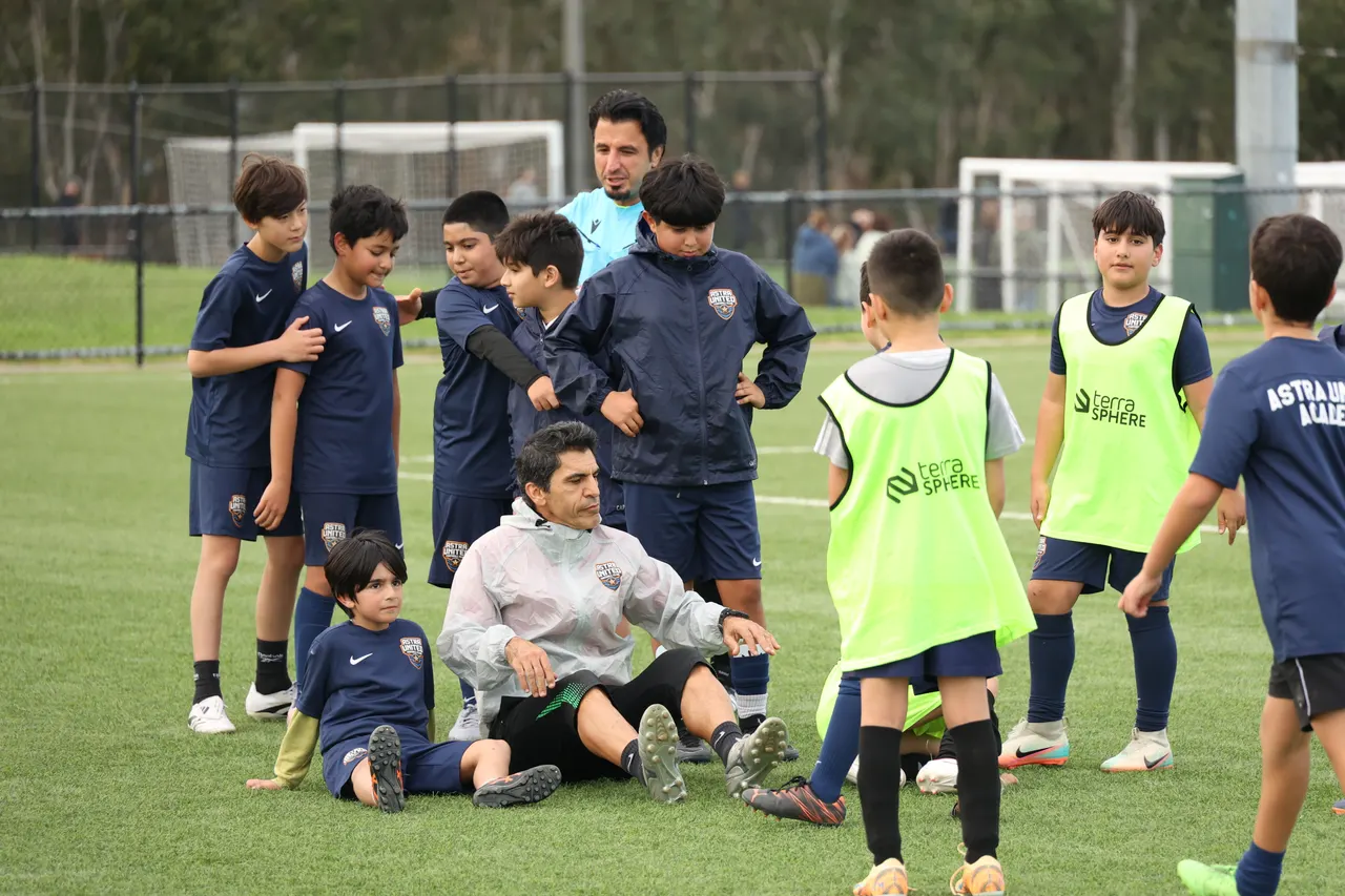 Young Astra United Academy players in navy kit and Academy bibs with their coaches during a Mini-Kickers session at Darebin